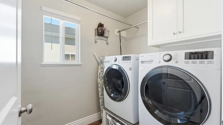 Laundry area featuring white cabinetry, a window, and a clothes hanging rod