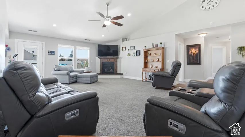 Vaulted ceilings with recessed lighting, ceiling fan, and a fireplace with a stone surround