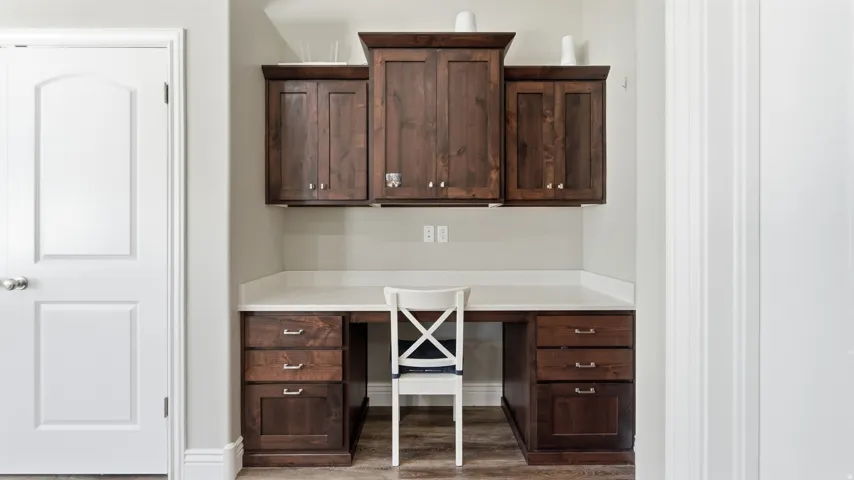 Built-in desk featuring dark wood-finish cabinetry, a light-toned countertop, and recessed lighting
