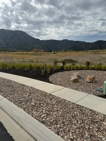 Landscaped property with gravel and stone elements, a paved walkway, and distant mountain scenery