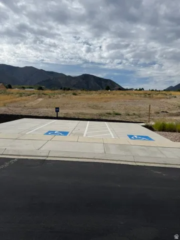 Paved parking area with concrete pads and marked spaces, framed by natural landscaping and distant mountains