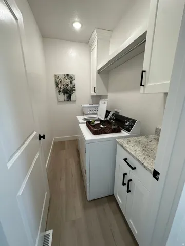 White shaker-style cabinetry, light wood-finish flooring, recessed lighting, and a light-toned countertop