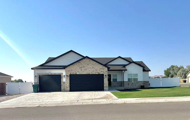 Contemporary exterior featuring brick and horizontal siding accents, a two-car garage, and a manicured lawn