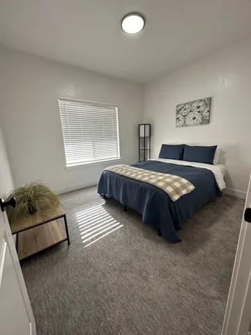 Recessed ceiling light, textured gray carpeting, window with horizontal blinds, and white wall finishes