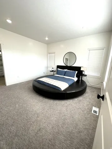 Recessed lighting, large windows, light grey carpeting, white trim, and white walls
