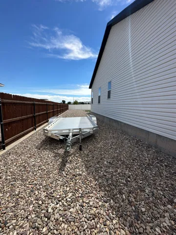 Side yard featuring gravel ground cover, a wood fence, and a white vinyl siding exterior