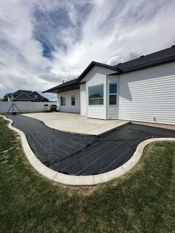 Expansive concrete patio with a curved, landscaped border