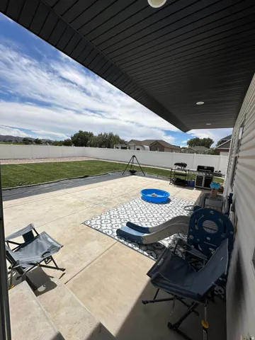 Expansive concrete patio with a covered outdoor area, offering direct access to a fenced grassy yard
