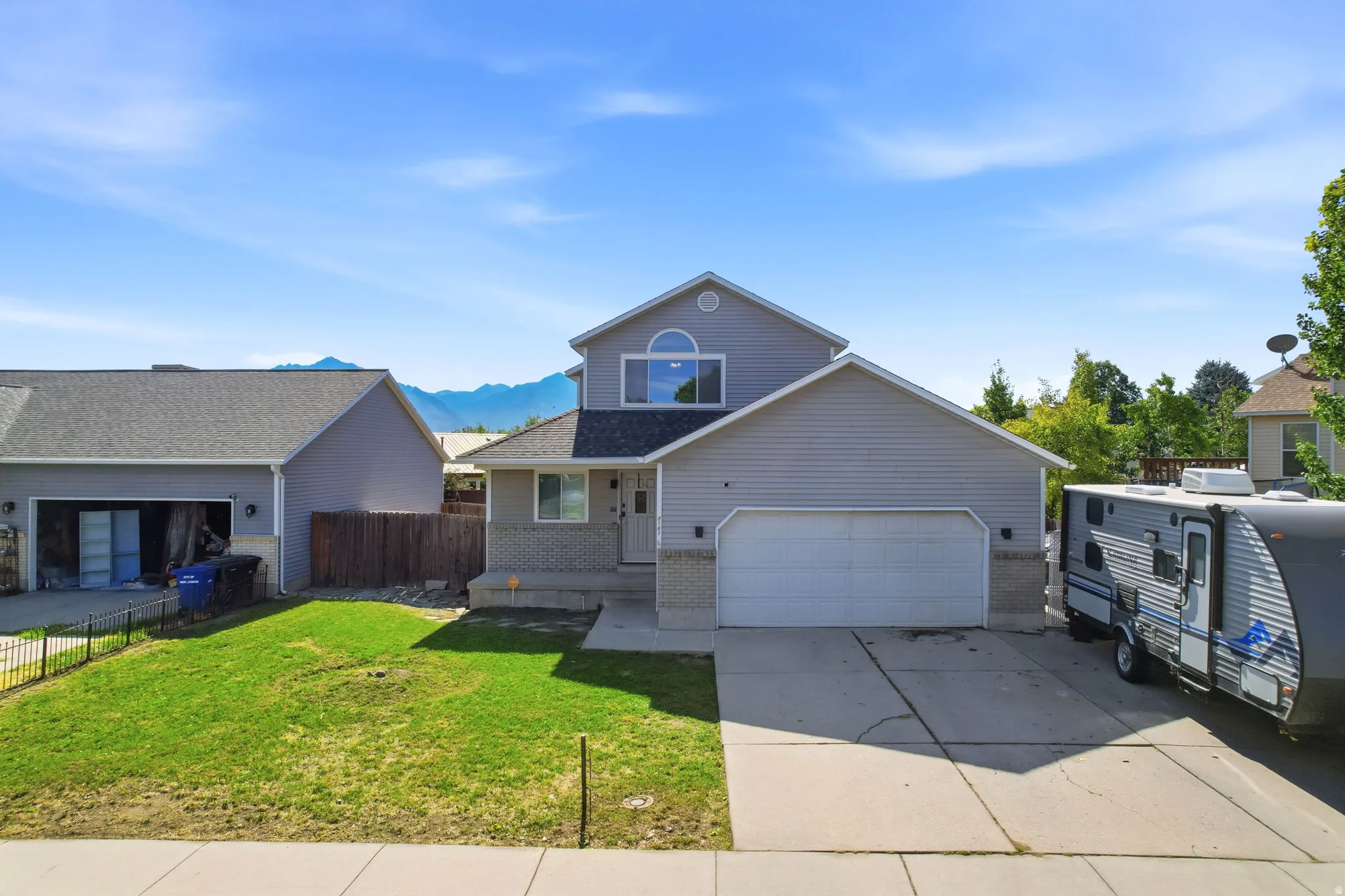 Two-story residence featuring light gray siding, an attached two-car garage, and a concrete driveway