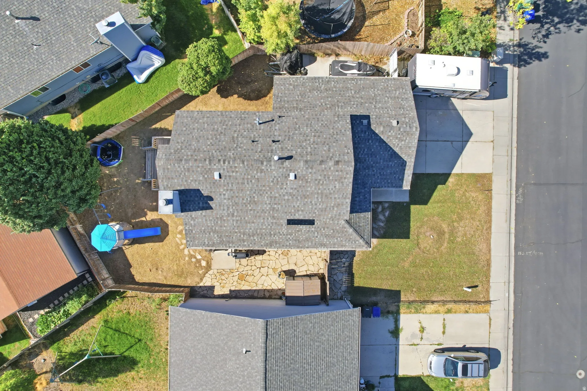 Paved driveway, mature trees, and a stone patio