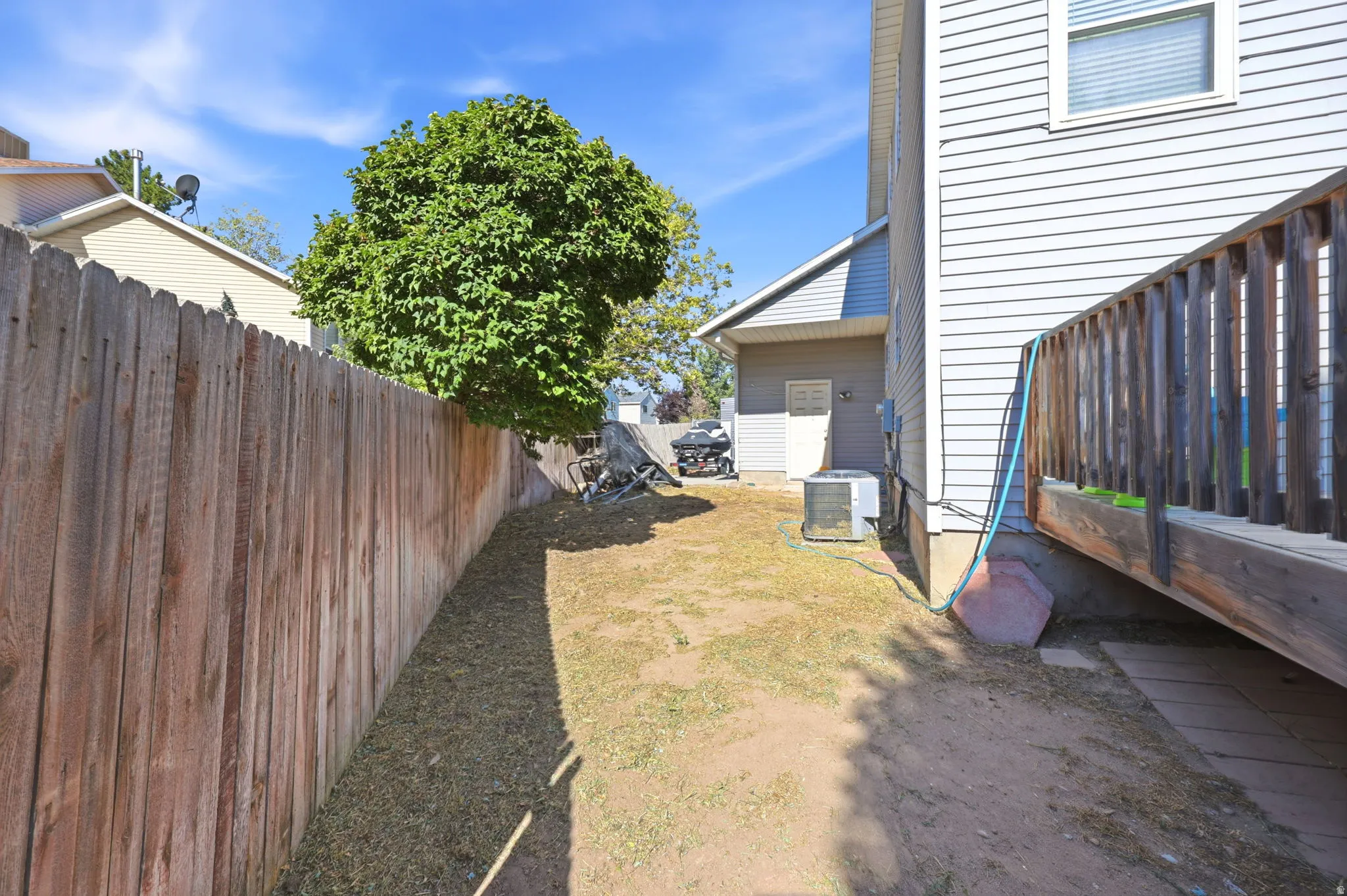 Private outdoor area featuring a wood fence, mature tree, and elevated wood deck