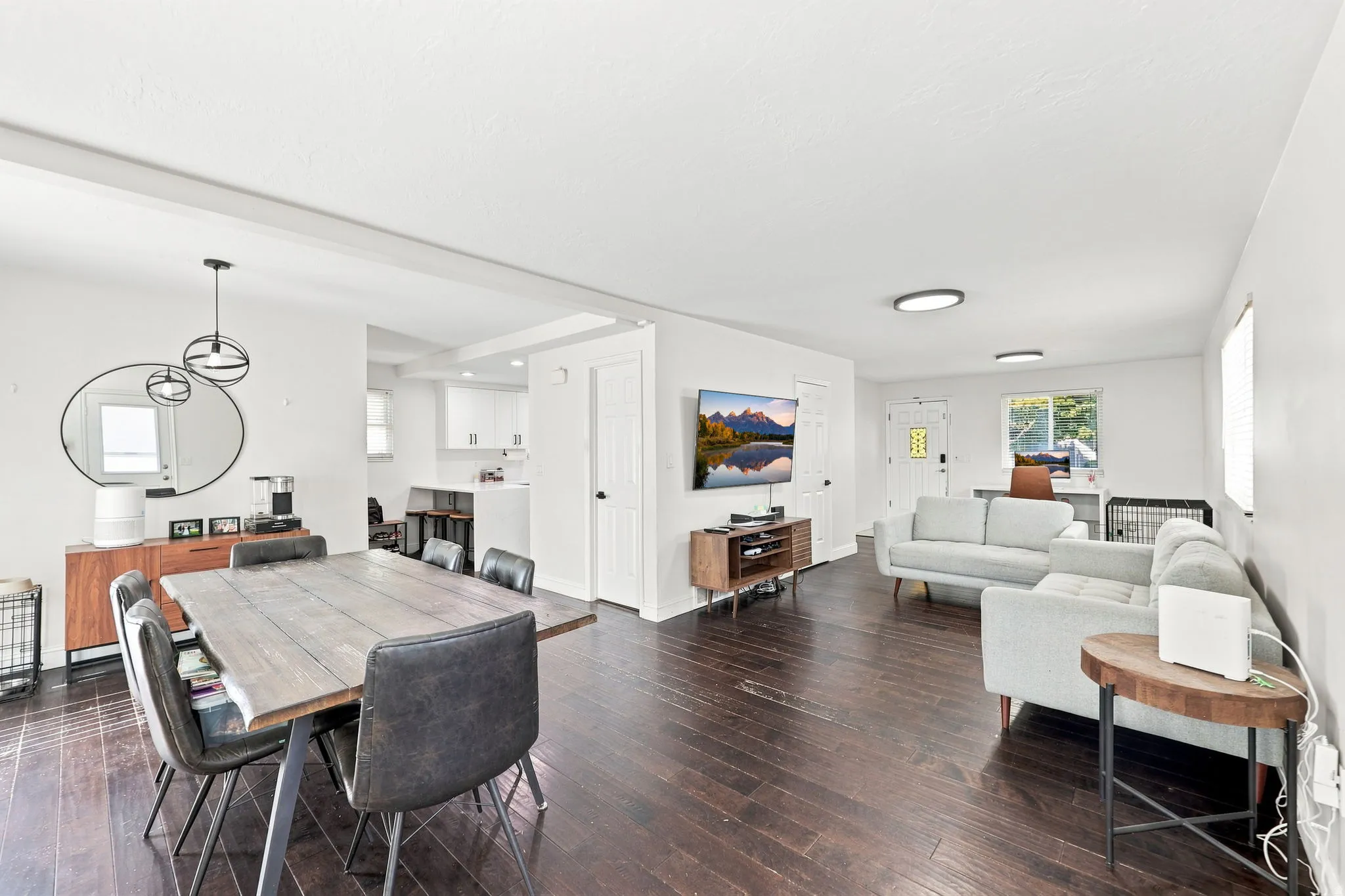 Expansive open-concept living area featuring dark wood-finish flooring, recessed lighting, and a modern pendant light fixture