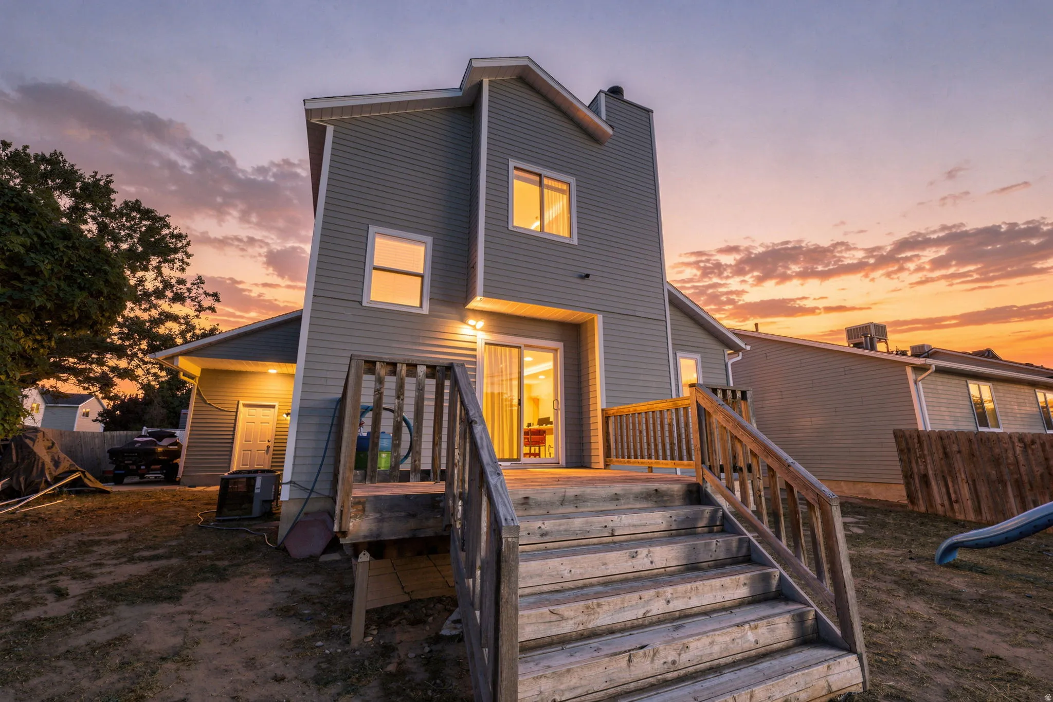 Multi-level home with horizontal siding, a two-story rear facade, and a wood deck with stairs
