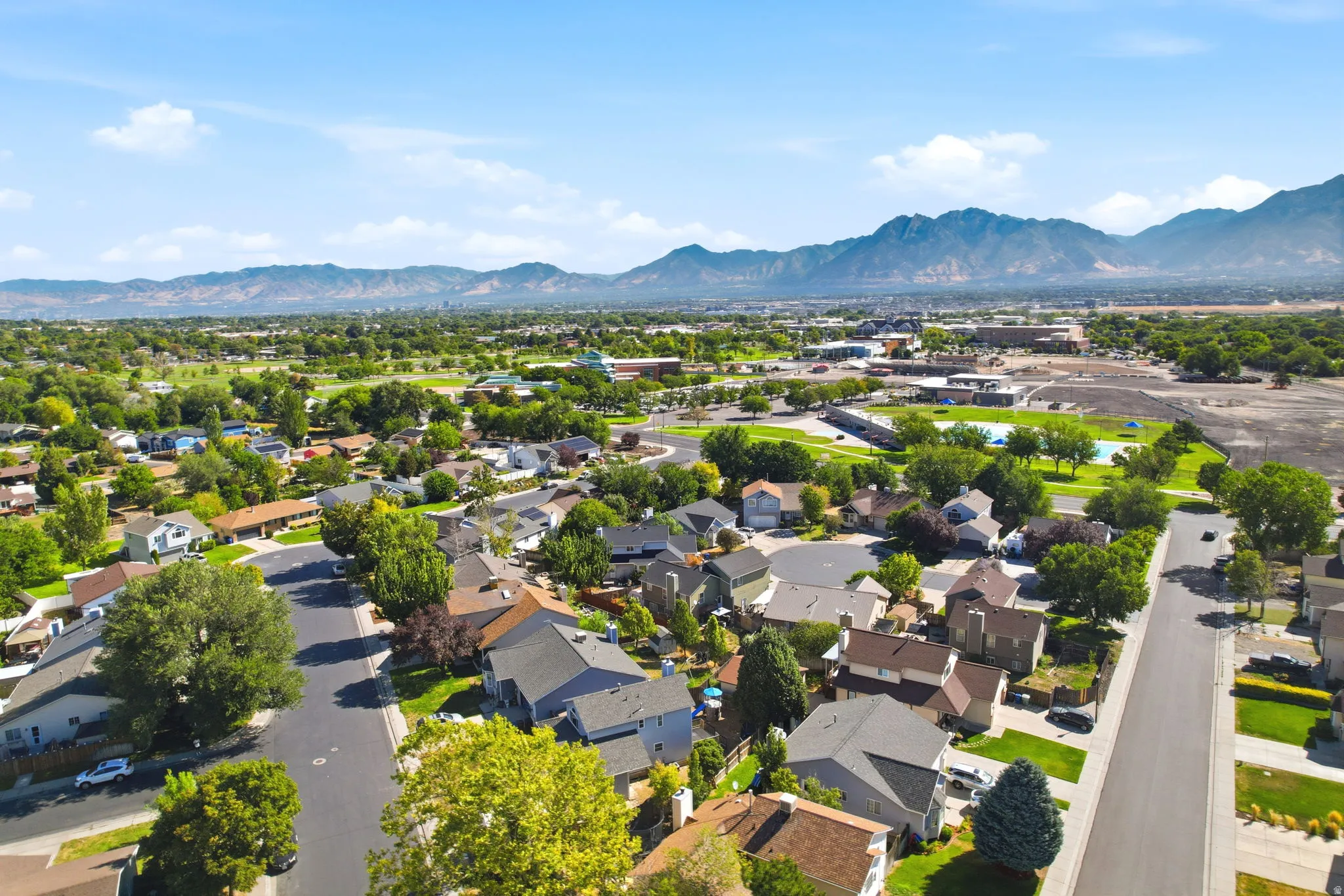 Residential neighborhood with mature trees, mountain backdrop, and clear skies