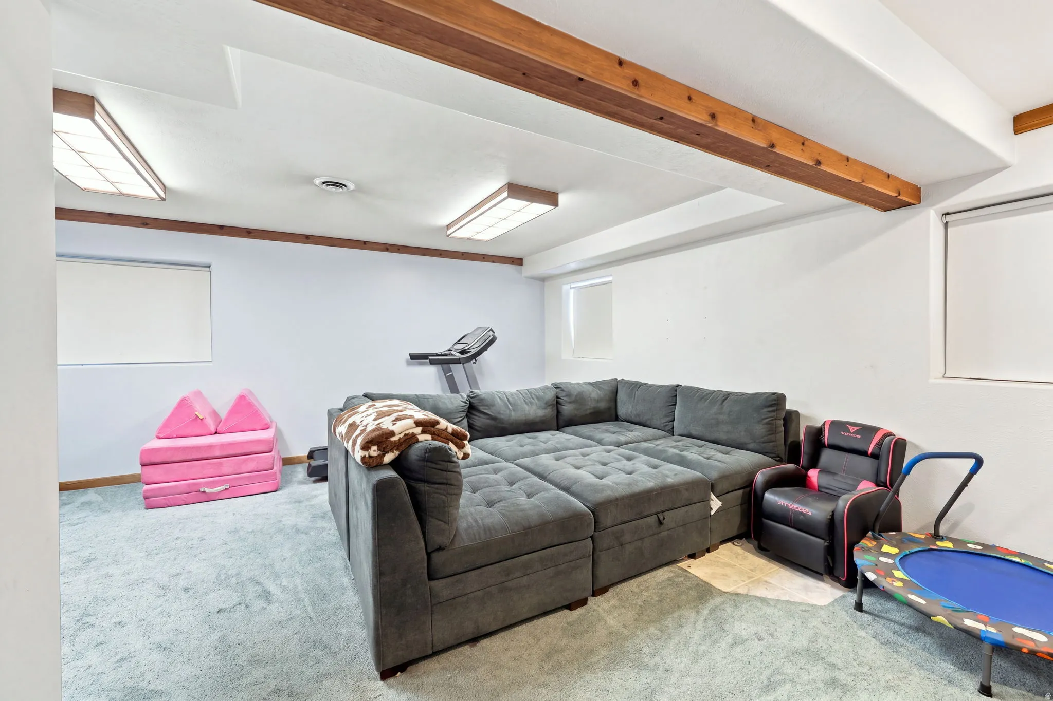 Finished lower level featuring exposed wood beams, recessed lighting, and wall-mounted windows