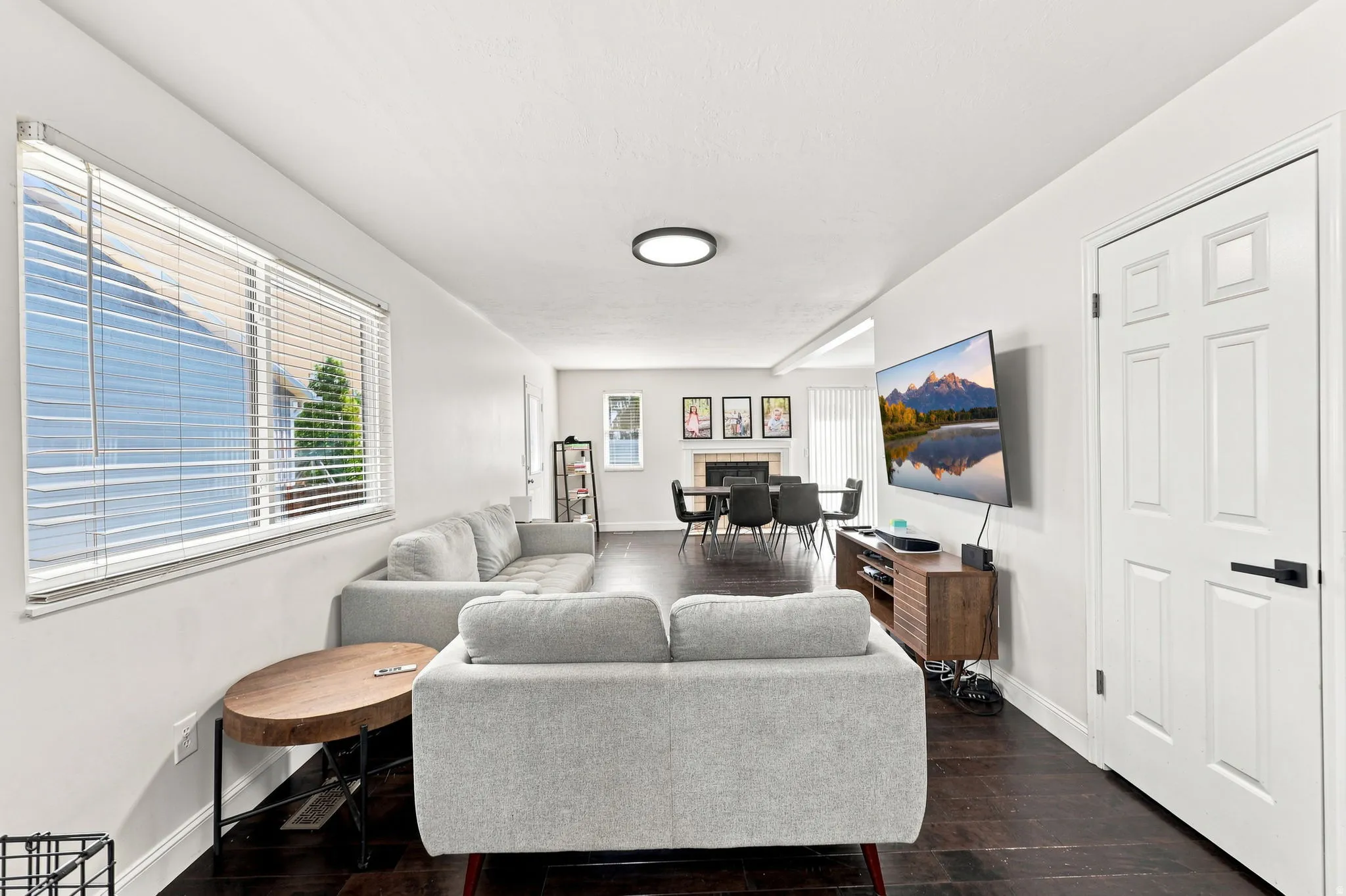 Expansive living area featuring dark wood-finish flooring and a large window with horizontal blinds