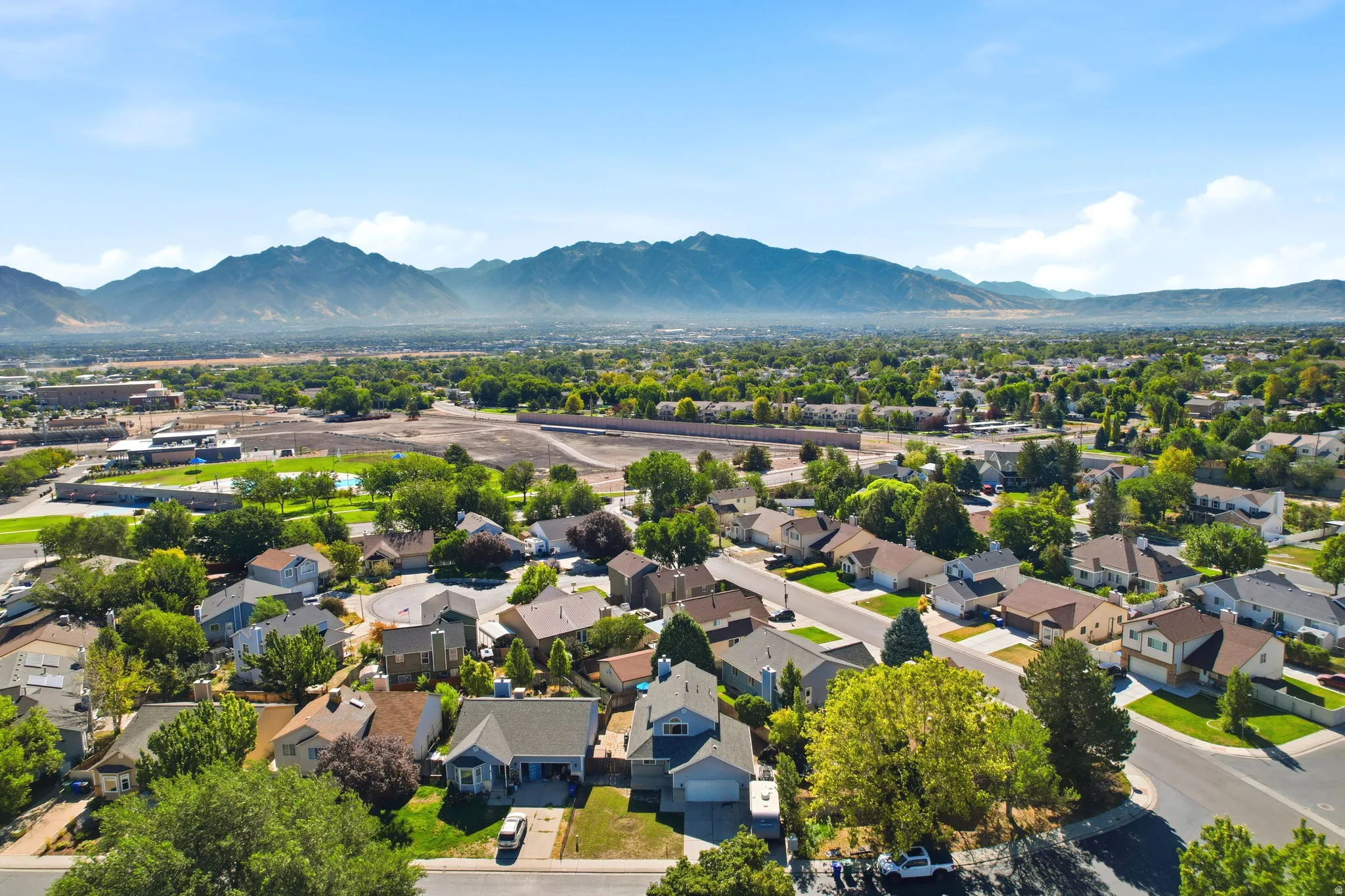 Mountain backdrop with a residential neighborhood featuring established homes, mature trees, and paved streets