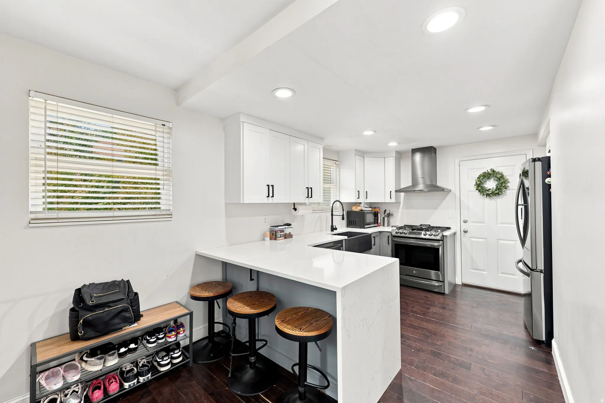 Modern kitchen featuring white cabinetry, stainless steel appliances, a white solid surface countertop, wood-finish flooring, and recessed lighting