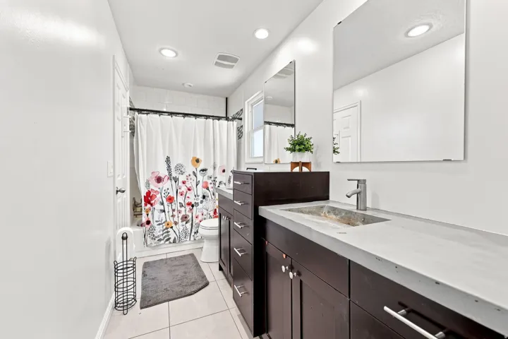 Dark wood-finish vanity with integrated sink, modern chrome faucet, and rectangular mirrors
