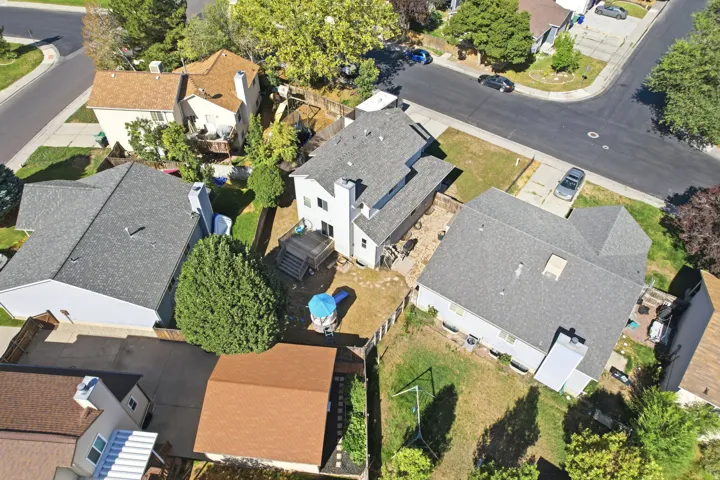 Asphalt shingle roof, paved driveway, concrete patio, wood fencing, mature trees