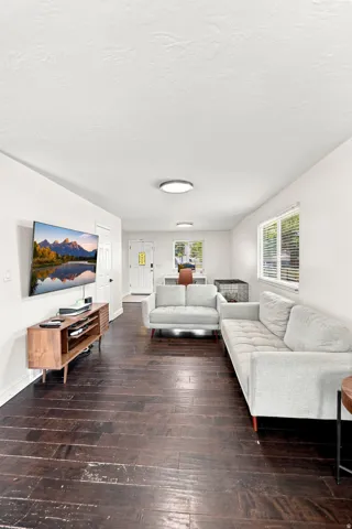 Dark wood-finish flooring throughout, white walls, and multiple windows with blinds