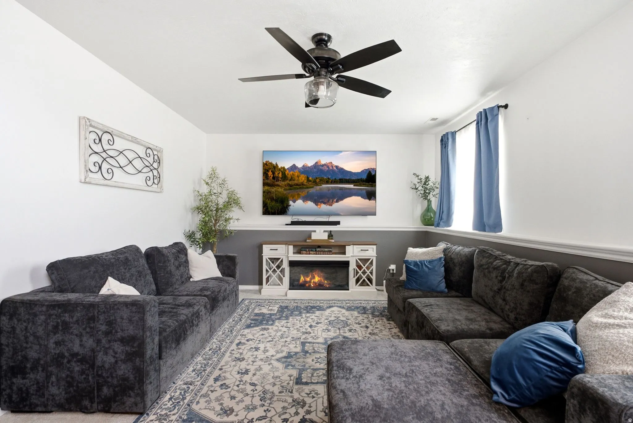 Recessed lighting, wood-finish flooring, built-in entertainment console with electric fireplace, ceiling fan with integrated lighting, and a window for natural light