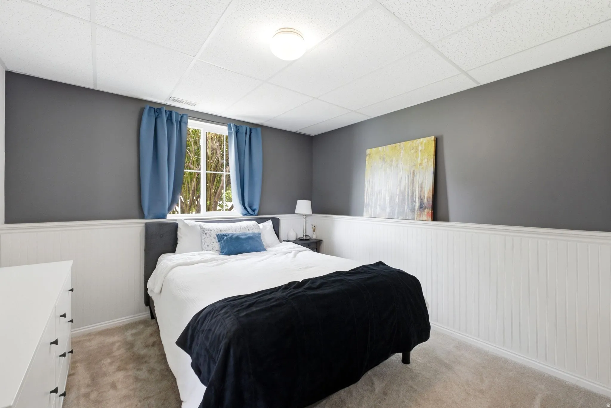 Window with natural light, textured ceiling, vertical paneling detail, wall-mounted lighting fixture, and carpeted flooring