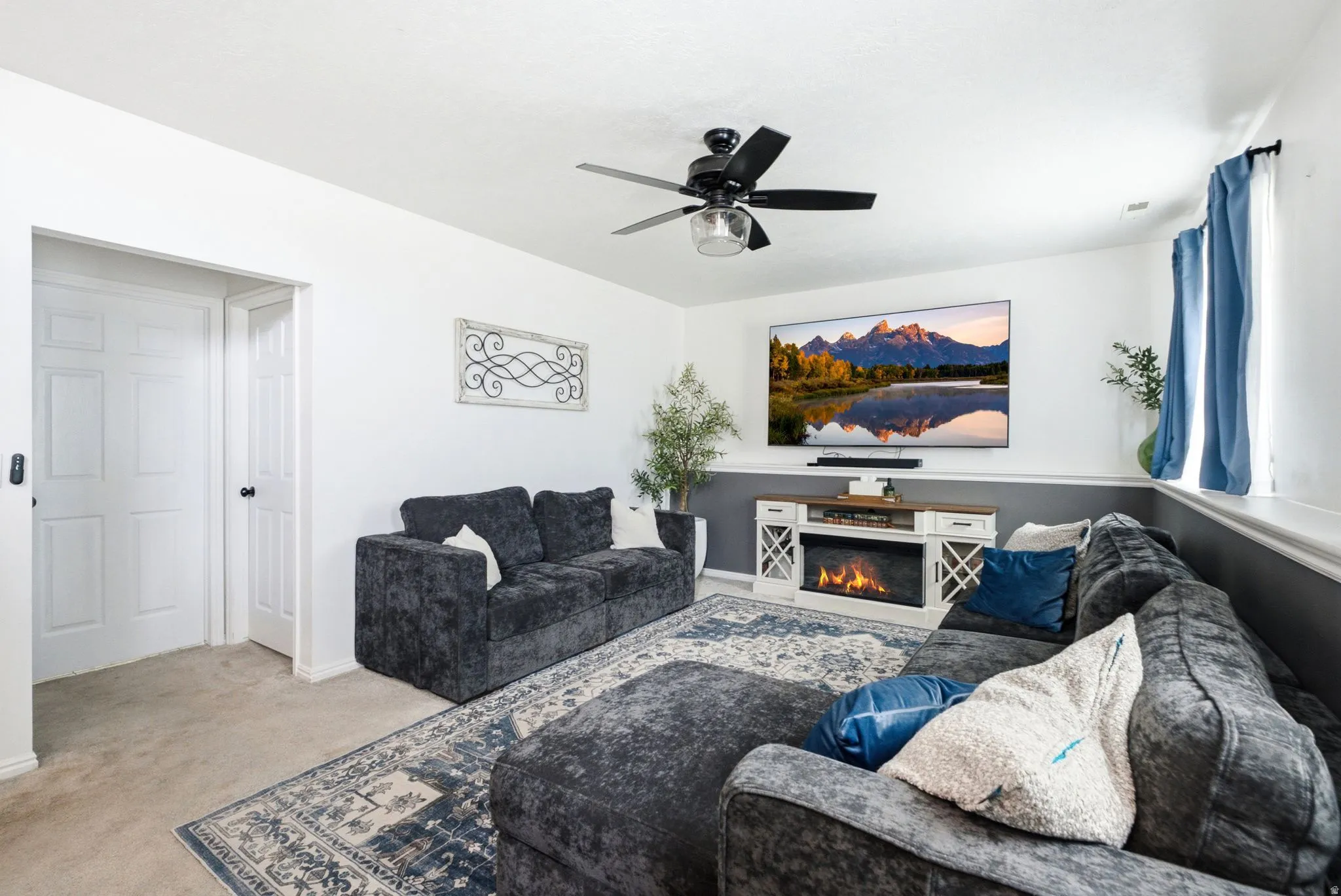 Recessed lighting, ceiling fan with integrated lighting, wall-mounted television, and a built-in electric fireplace