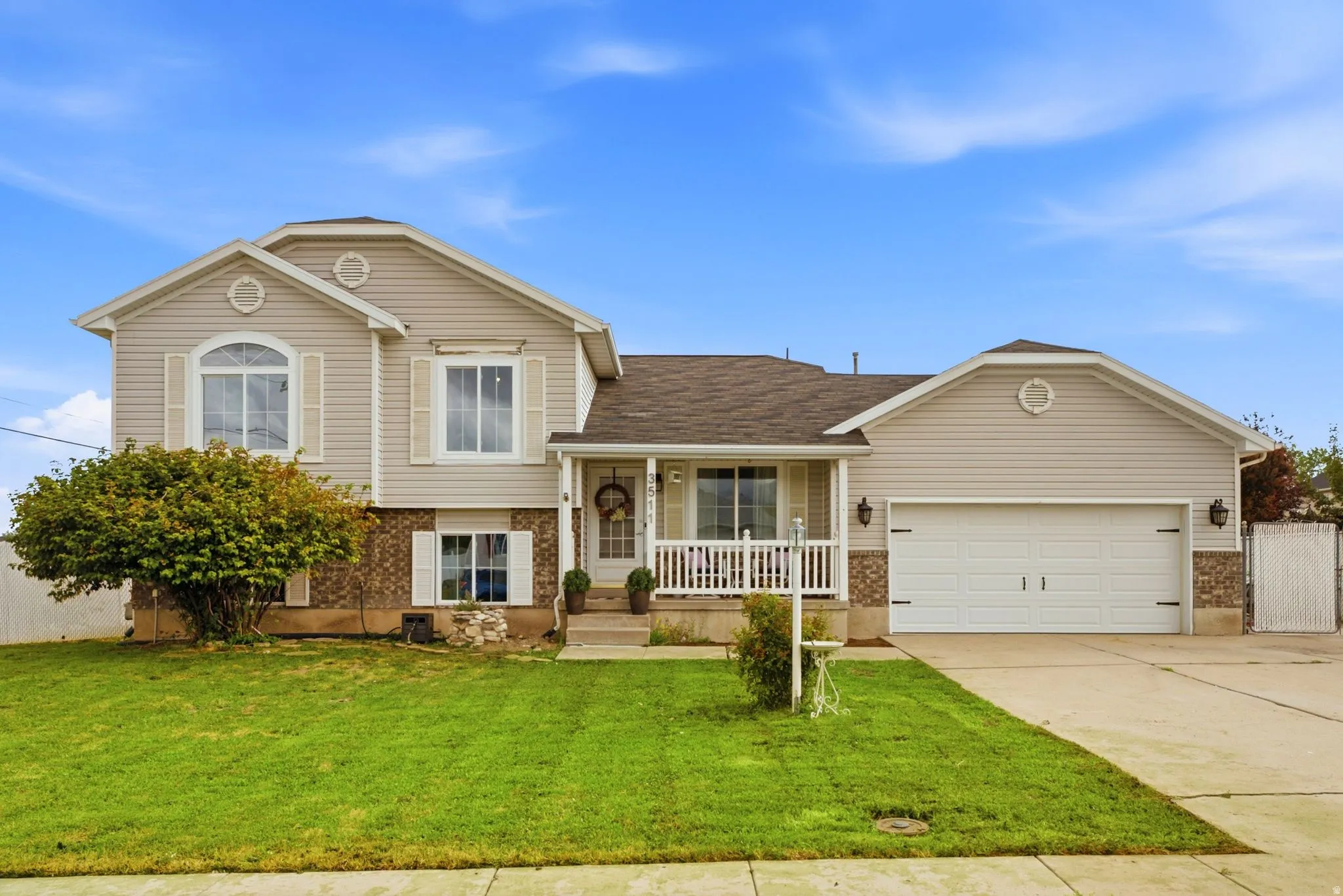 Two-story residence featuring light-toned siding, a two-car garage with carriage-style doors, and a covered front porch