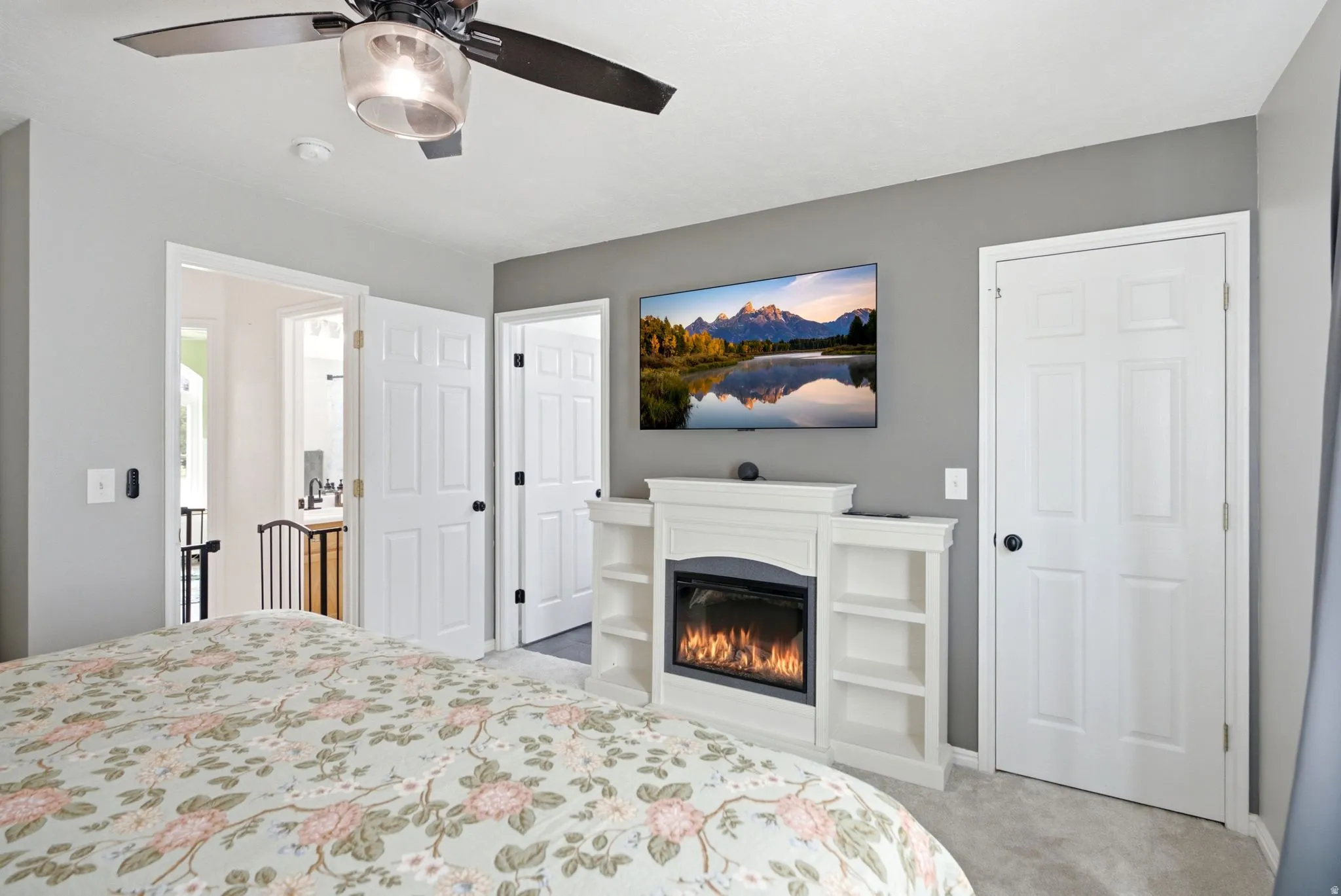 Ceiling fan with integrated light fixture, built-in electric fireplace with mantle and shelving, and multiple paneled doors