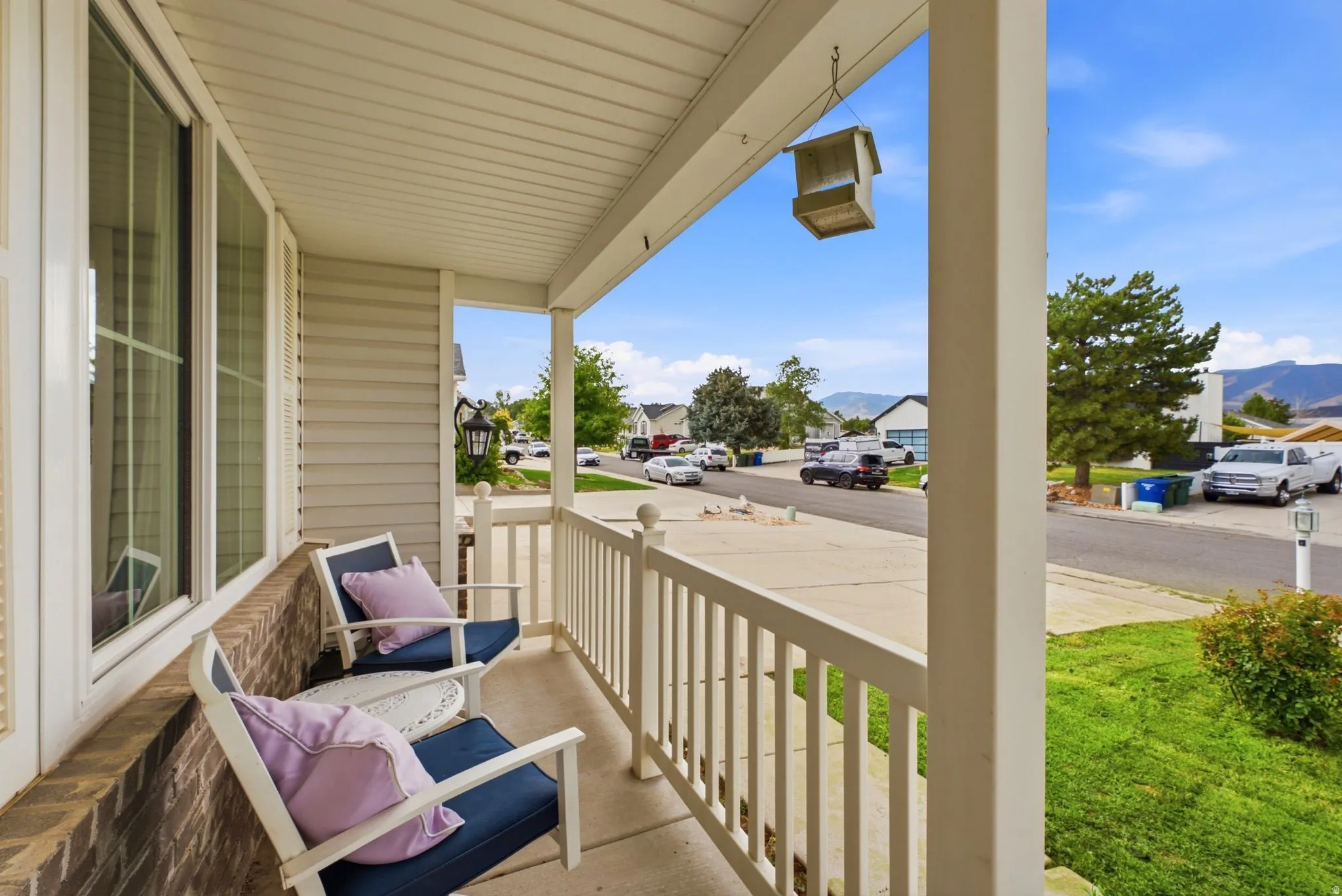 Covered front porch featuring white railings, brick detailing, and siding exterior