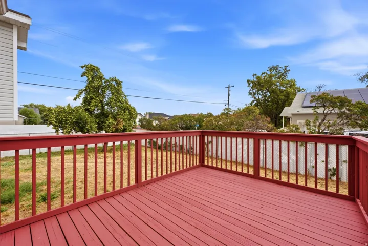 Expansive red-stained wood deck featuring a protective railing and a fenced-in yard area