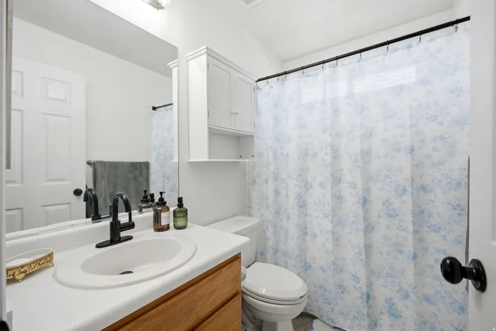 White vanity with a black matte faucet, built-in sink, and full-width mirror