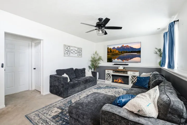 Recessed lighting, ceiling fan with integrated lighting, wall-mounted television, and a built-in electric fireplace