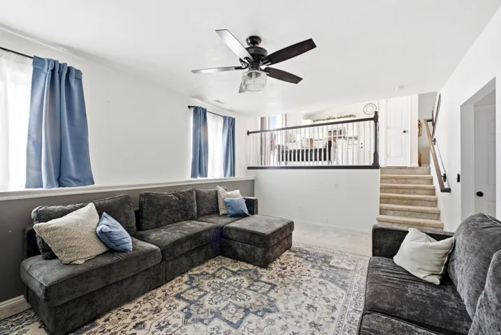 Recessed lighting, wood-finish railing, carpeted staircase, ceiling fan light fixture, and windows with natural light
