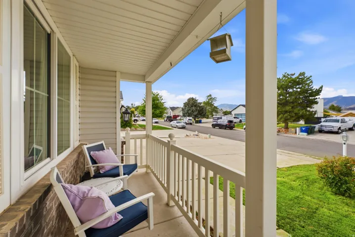 Covered front porch featuring white railings, brick detailing, and siding exterior