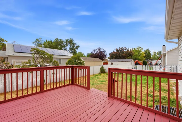 Expansive outdoor deck with red-stained wood flooring and matching railings