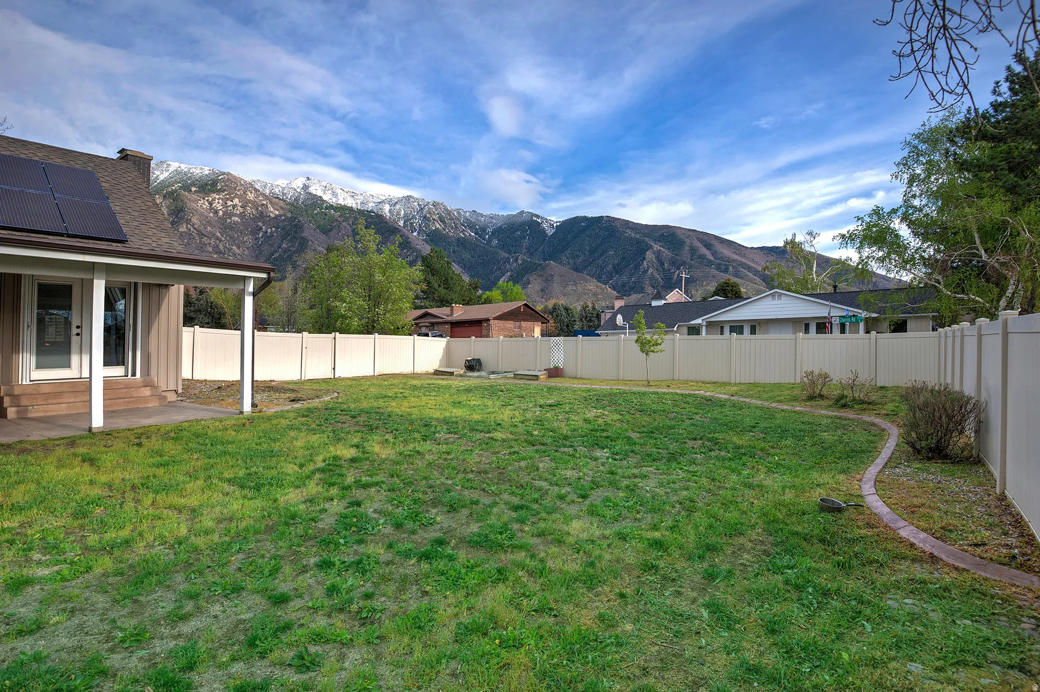 Expansive backyard featuring a manicured lawn, established landscaping, and a privacy fence