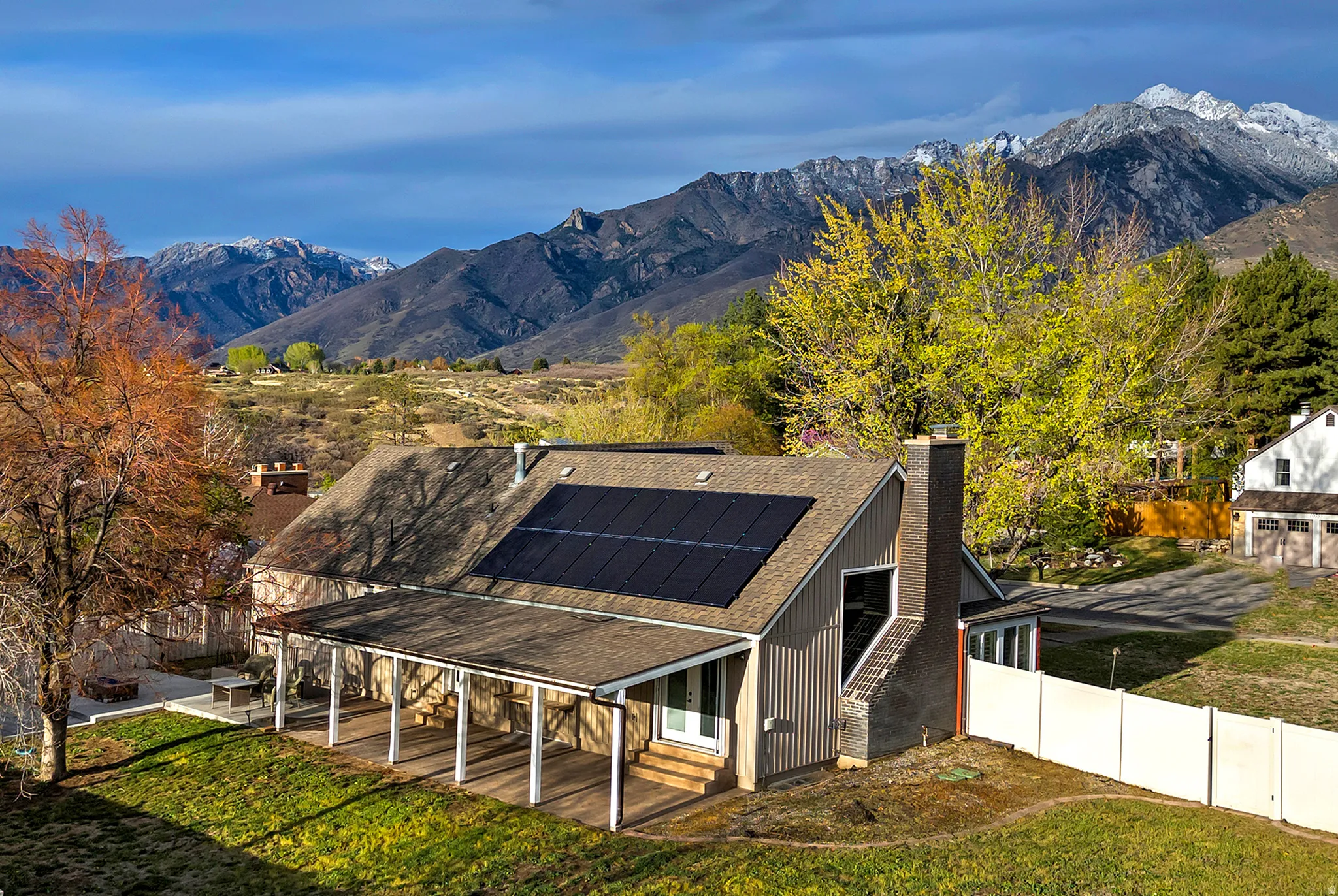 Exterior featuring a covered patio, solar panels, and a prominent chimney