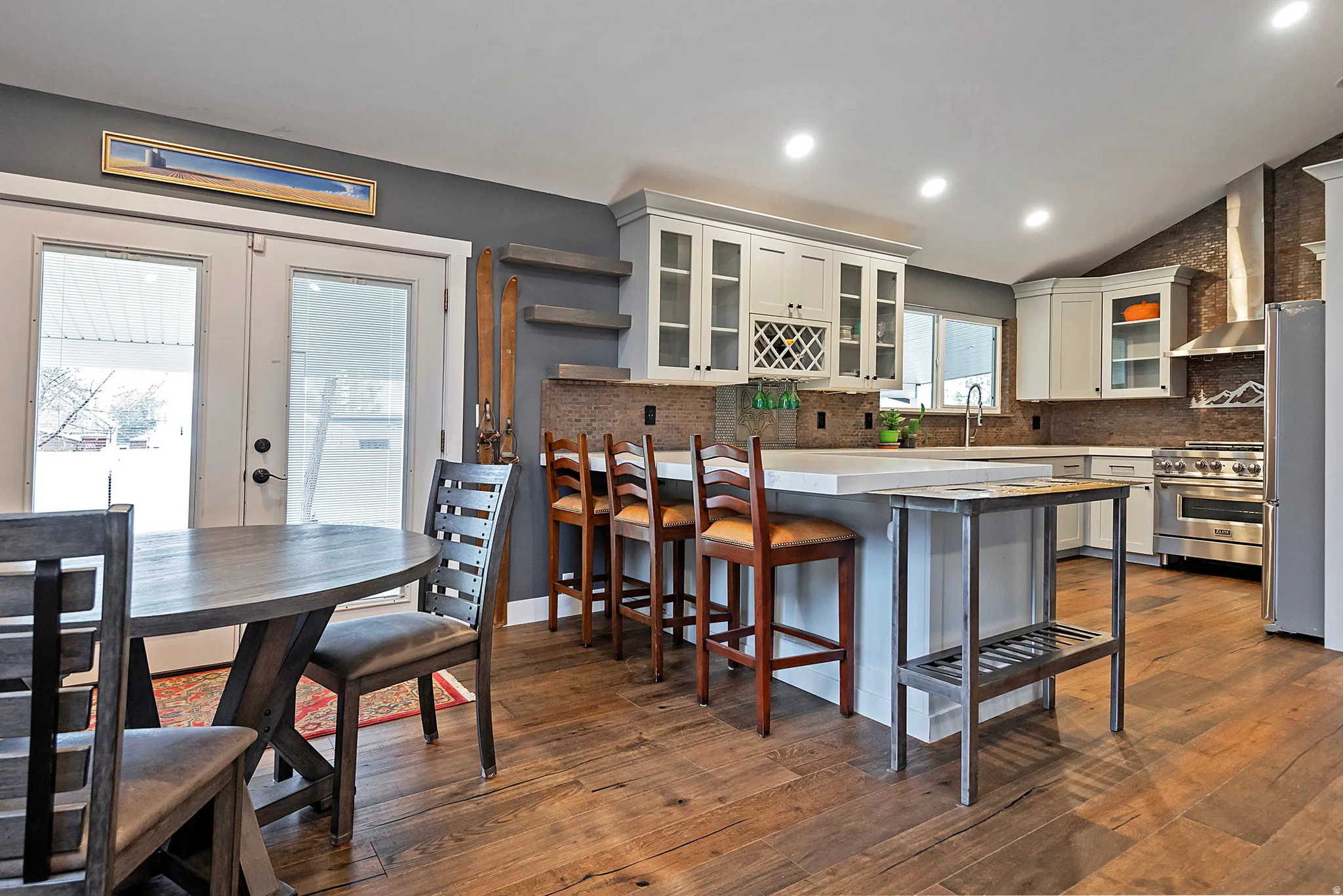 Open-concept kitchen with wood-finish flooring, white cabinetry, a large center island, and stainless steel appliances