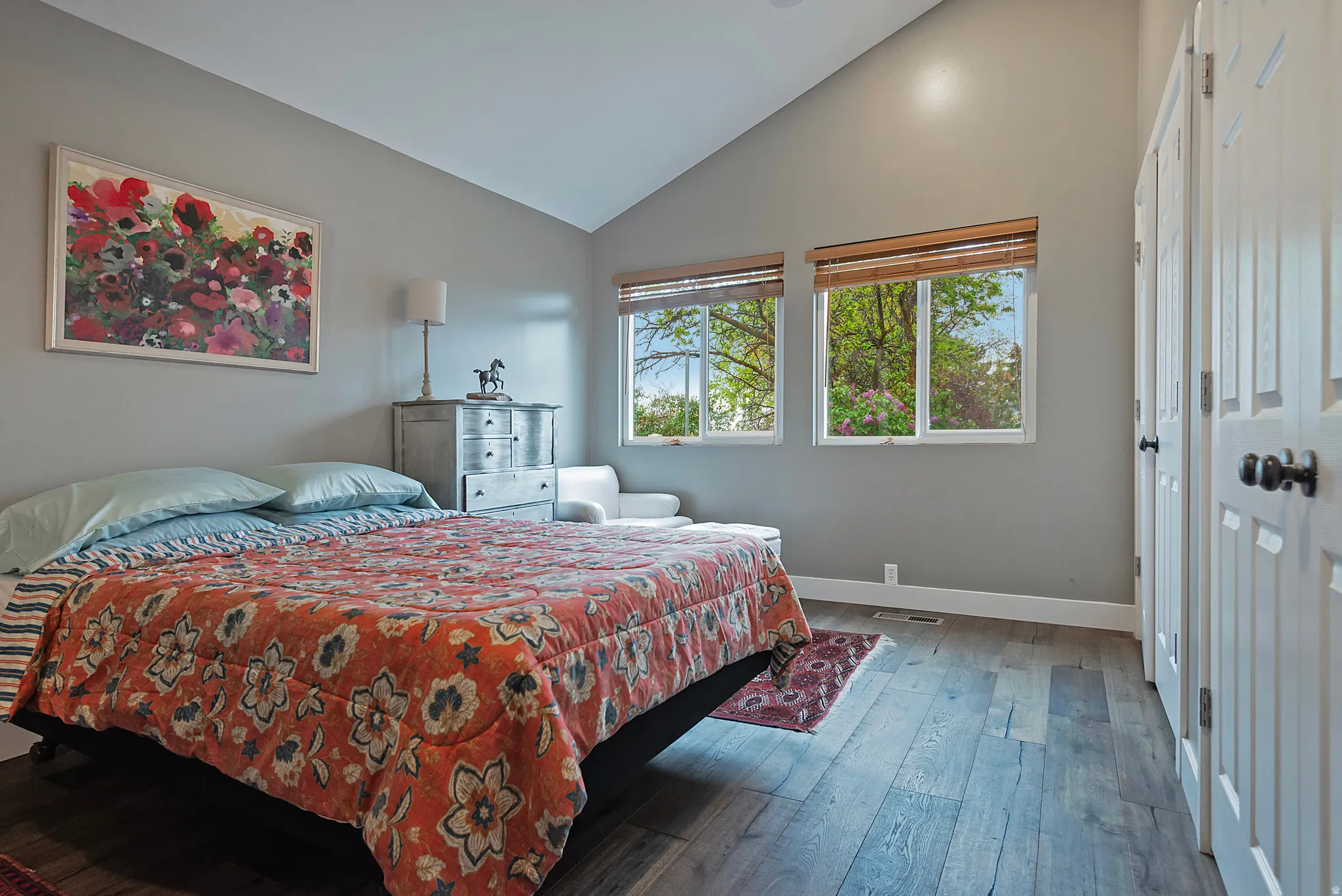 Vaulted ceiling with recessed lighting, wood-finish flooring, and dual windows with natural light