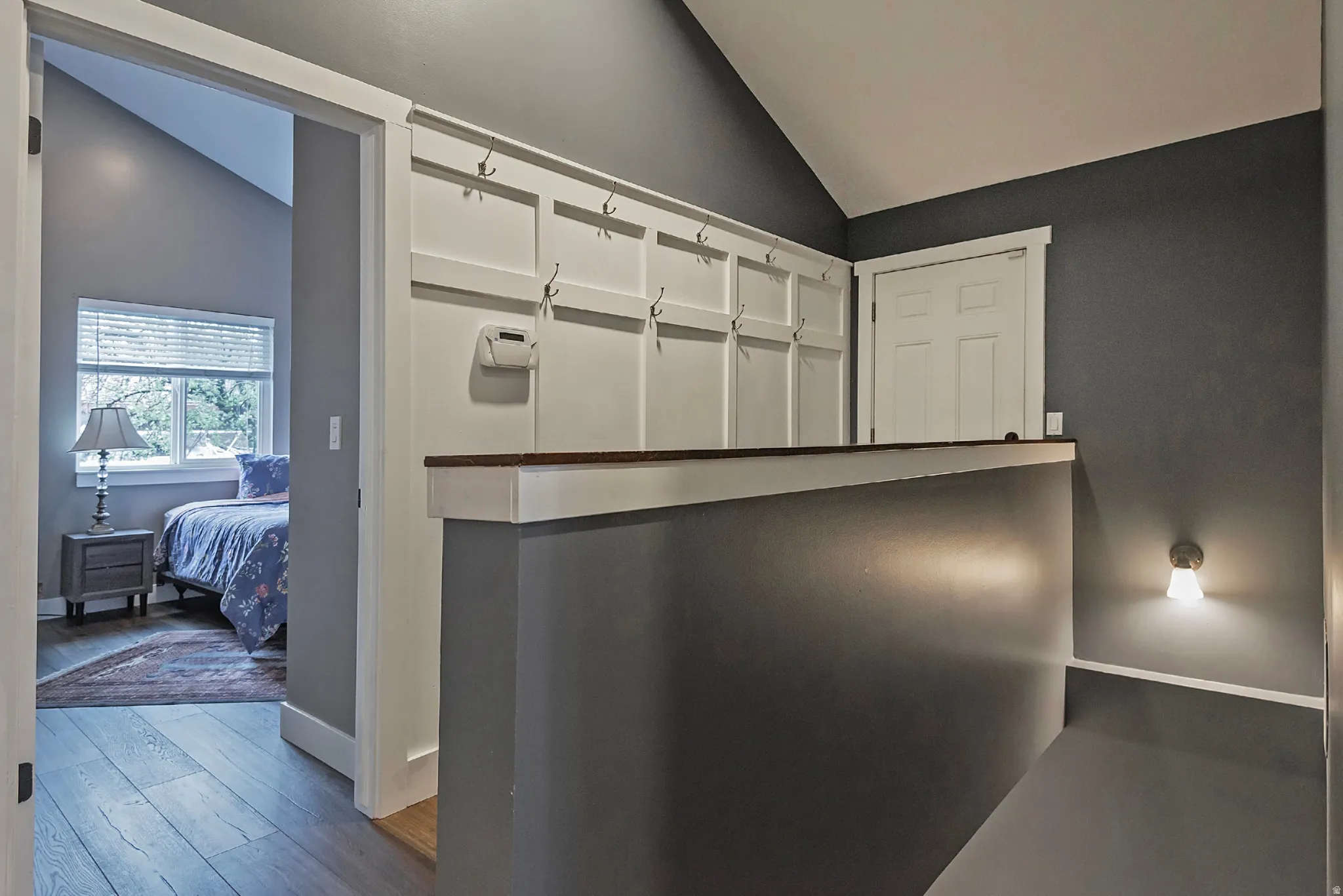 Wood-finish flooring, accent wall, built-in coat rack, wall-mounted light fixture, white interior door