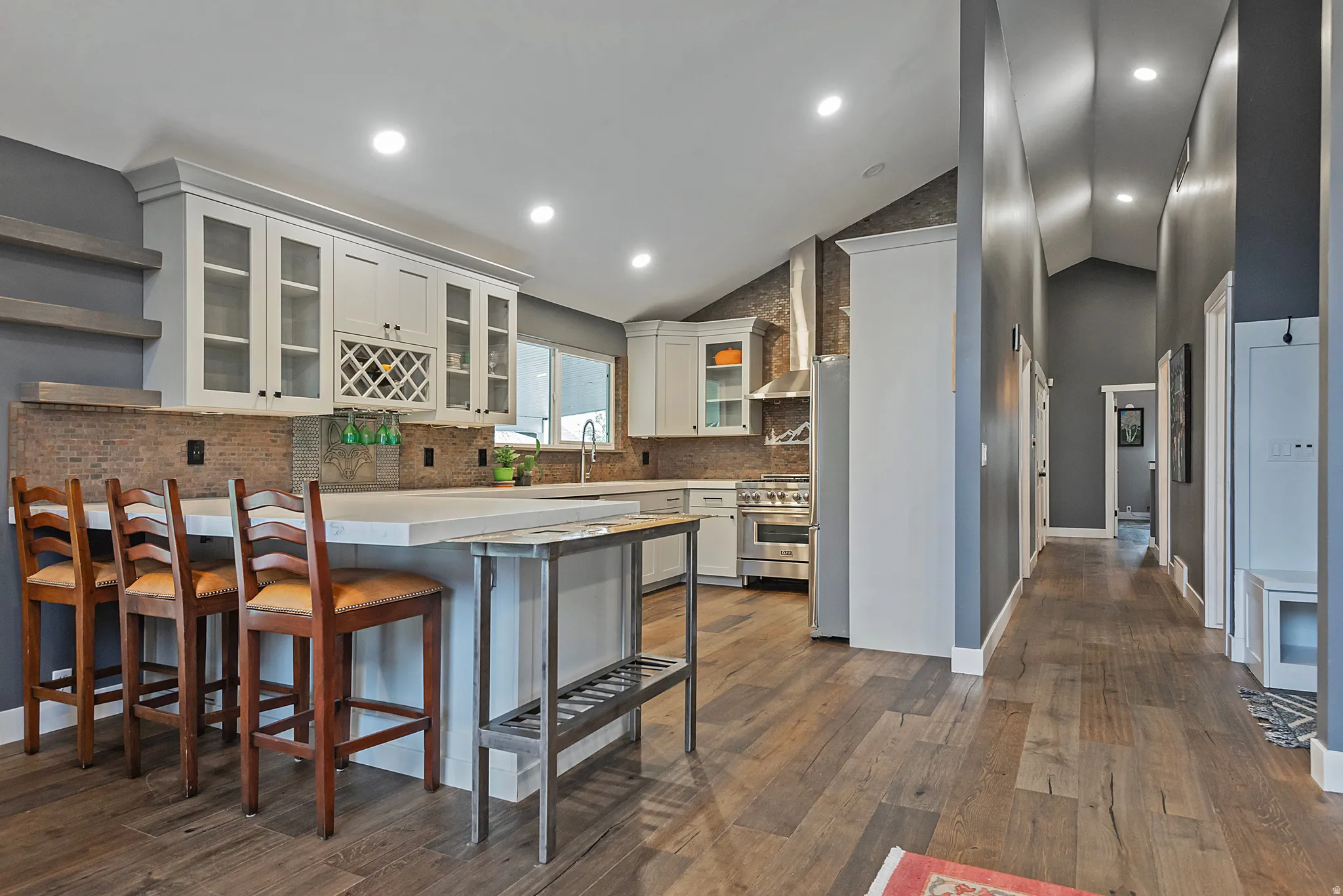 Gourmet kitchen with white cabinetry and stone backsplash