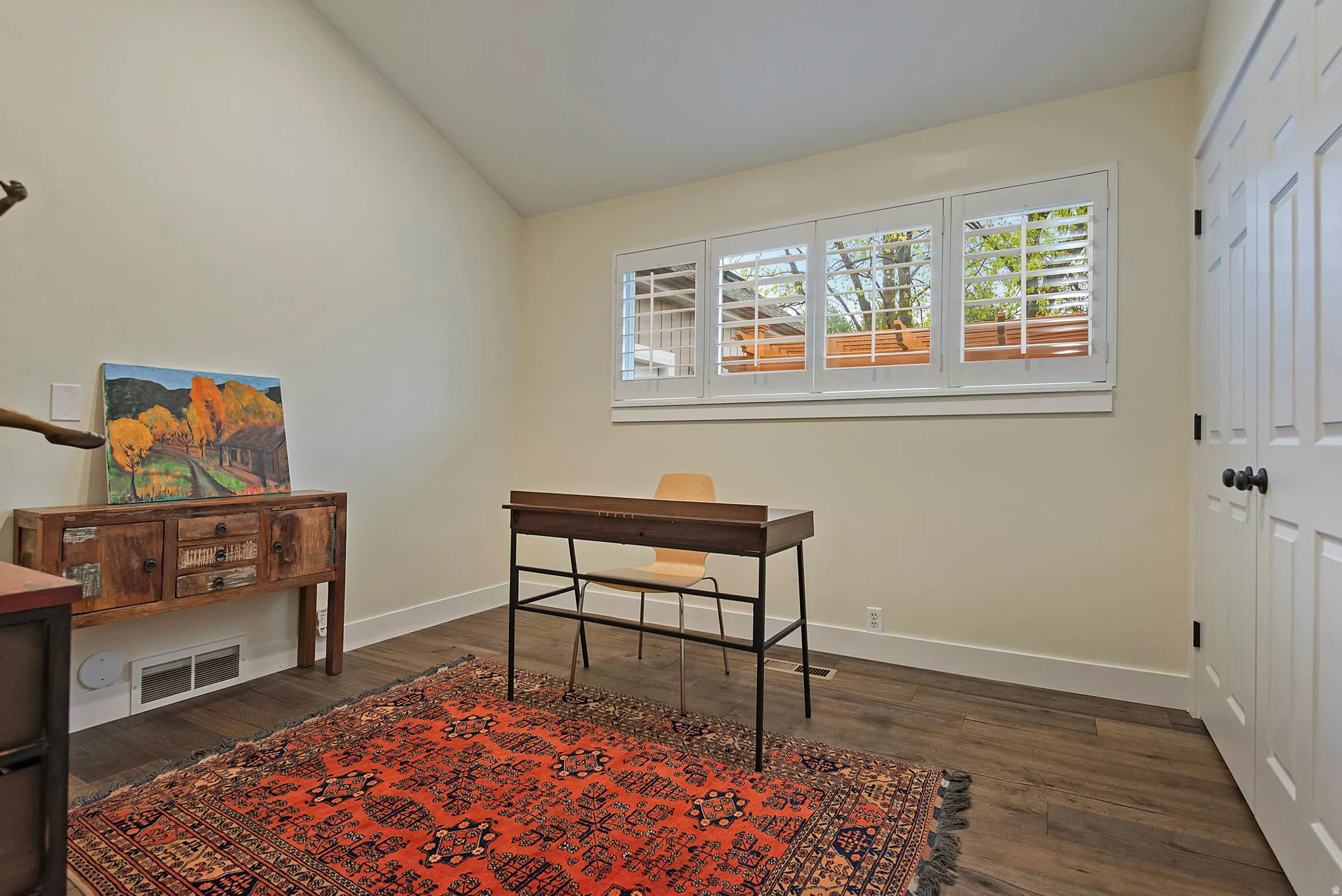 Vaulted ceiling, wood-finish flooring, white window shutters, and white paneled doors