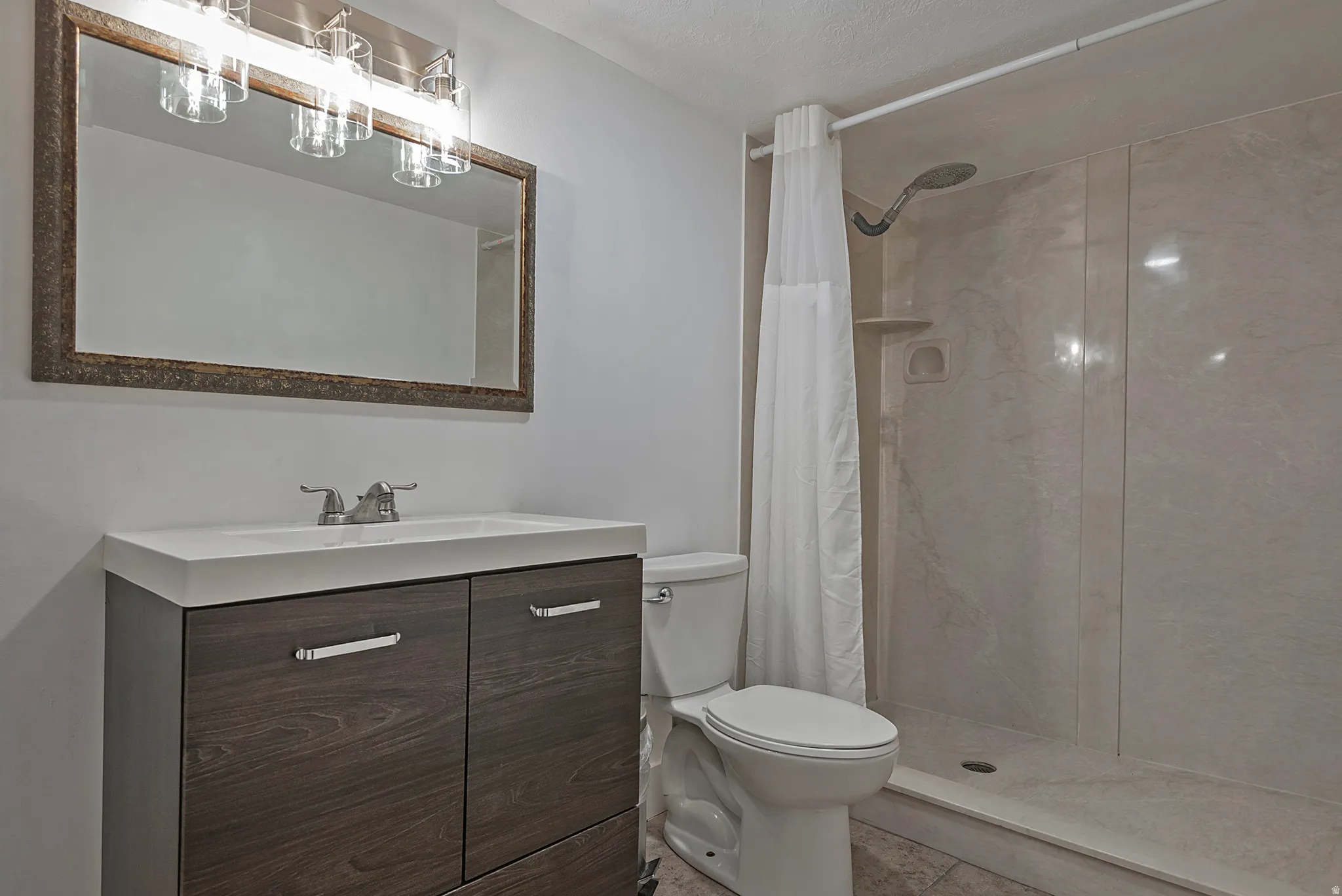 Modern vanity with integrated sink, wood-finish cabinetry, and brushed nickel hardware