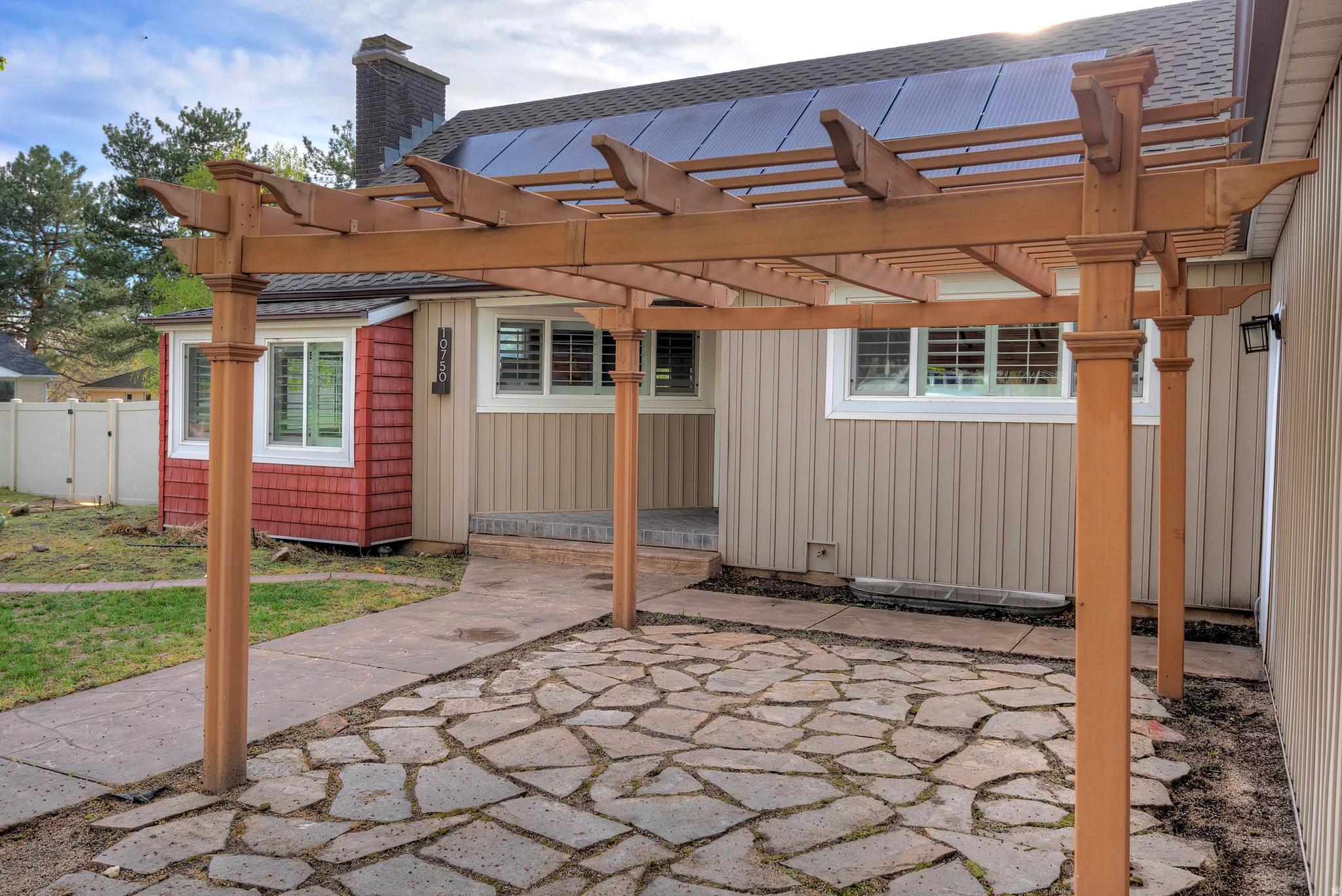 Wood pergola covering a flagstone patio with a concrete walkway