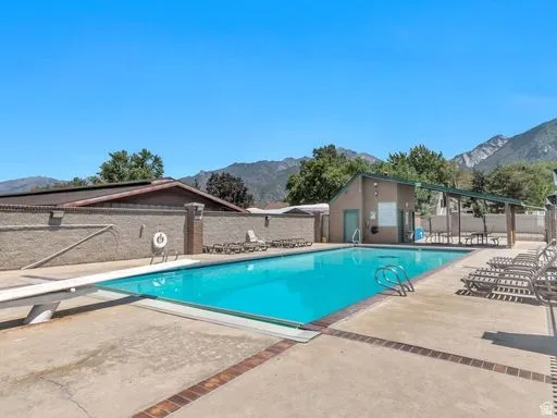 Community swimming pool with a diving board and surrounding concrete patio
