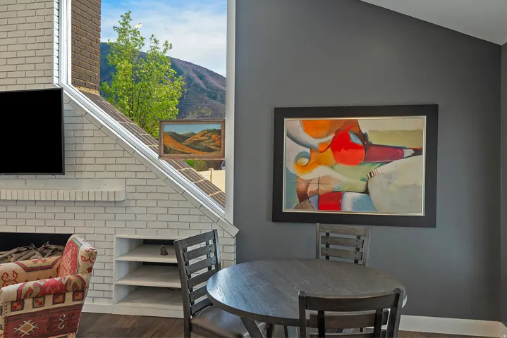 White brick fireplace with built-in shelving, wood-finish flooring, and a large window offering natural light