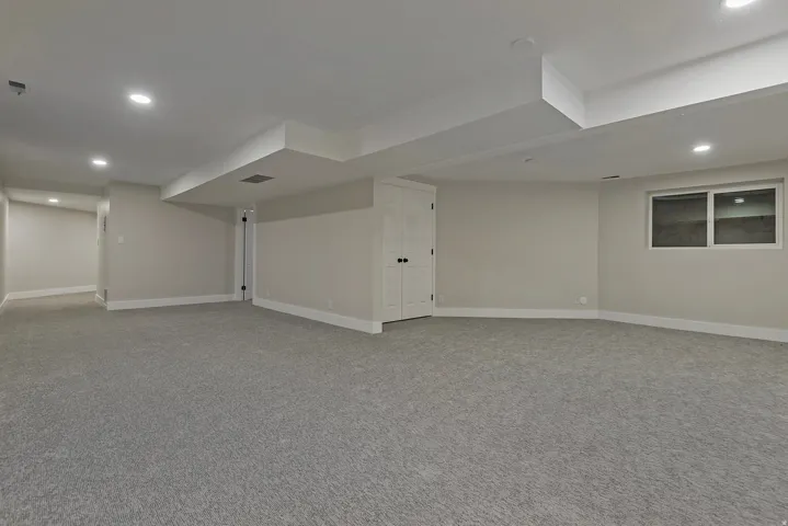 Spacious room featuring gray carpet, recessed lighting, and a white-framed window