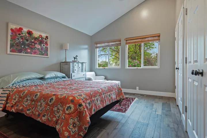 Vaulted ceiling with recessed lighting, wood-finish flooring, and dual windows with natural light